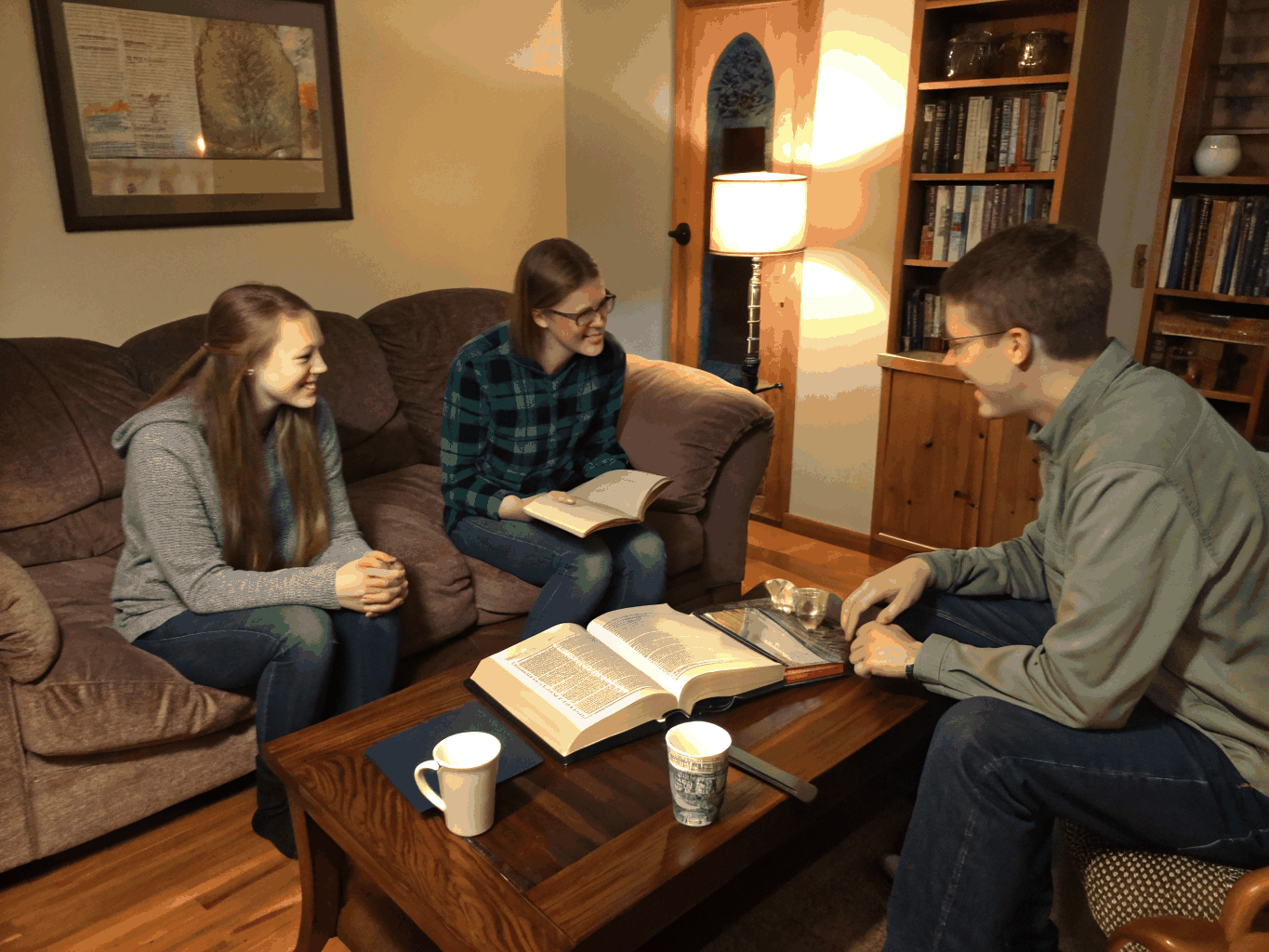 Small group sitting together in a warm living room sharing a meal